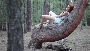 Худая рыжая девка в платье мастурбирует в лесу на дереве